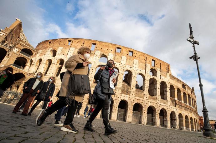Personas con mascarilla transitan por las inmediaciones del Coliseo de Roma.