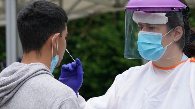 Un sanitario efectúa una PCR a un joven.