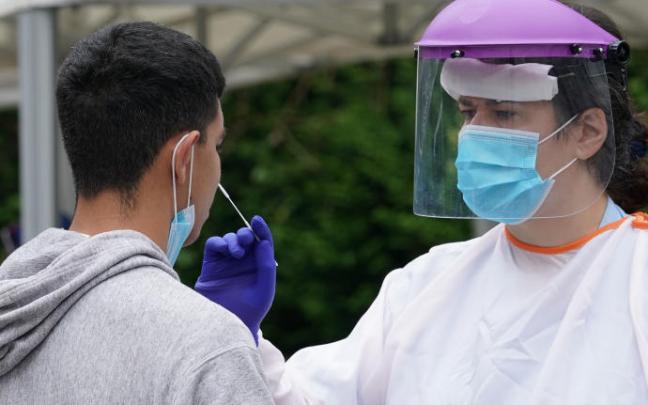 Un sanitario efectúa una PCR a un joven.