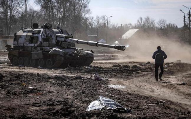 Un hombre pasea junto a un tanque destruido en la ciudad ucraniana de Trostianets.