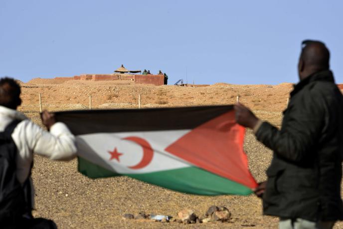 Dos hombres saharauis sostiene una bandera del Frente Polisario al noroeste del paso fronterizo de Guerguera