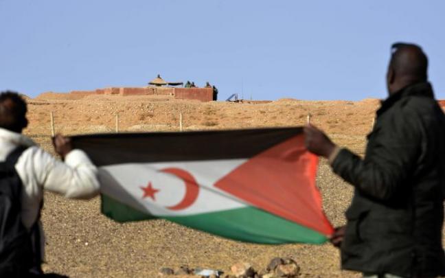 Dos hombres saharauis sostiene una bandera del Frente Polisario al noroeste del paso fronterizo de Guerguera