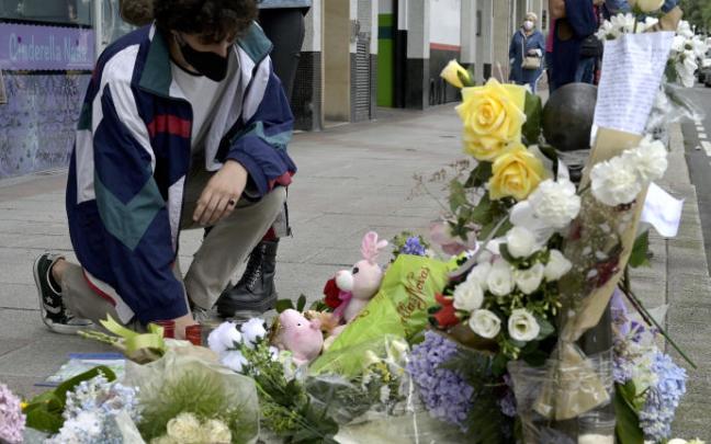 Un joven se arrodilla ante el altar colocado en la acera donde fue golpeado Samuel