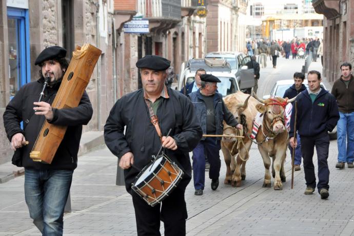 Txistularis y ganaderos paseando a la novilla por las calles antes del sorteo de la popular rifa de San Antón.