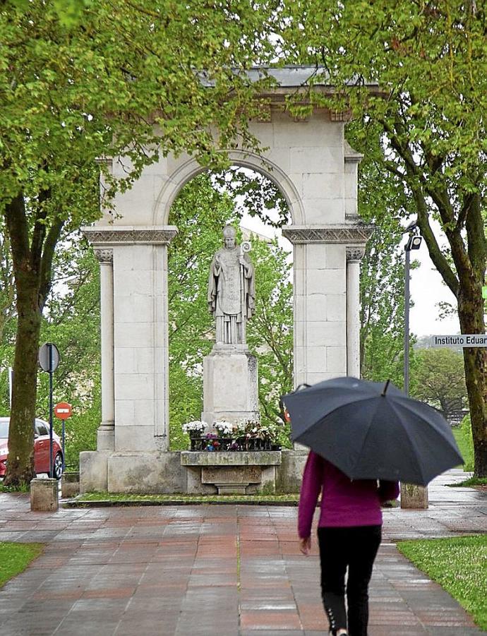 Una persona con paraguas junto al monumento del santo. Foto: J. Muñoz