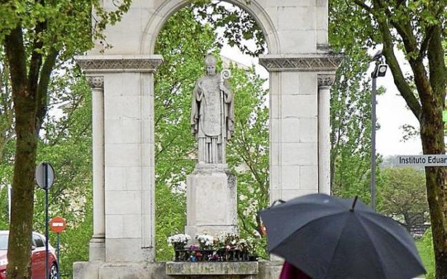 Una persona con paraguas junto al monumento del santo. Foto: J. Muñoz