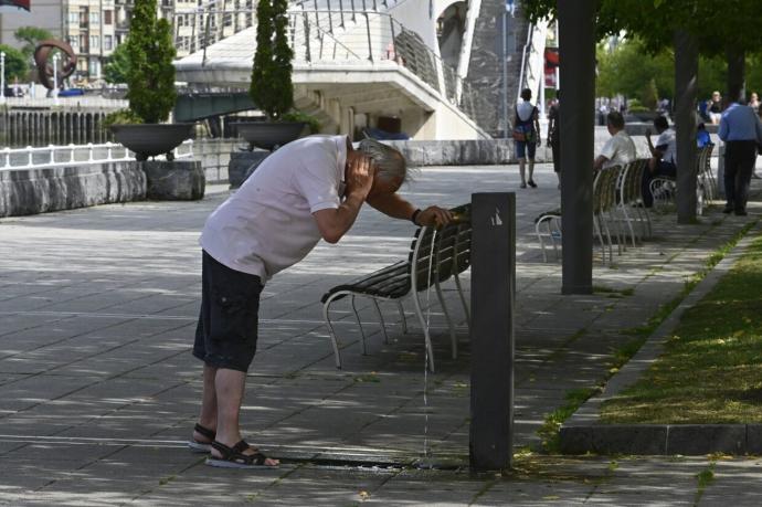 Un hombre se refresca en la fuente para combatir el calor