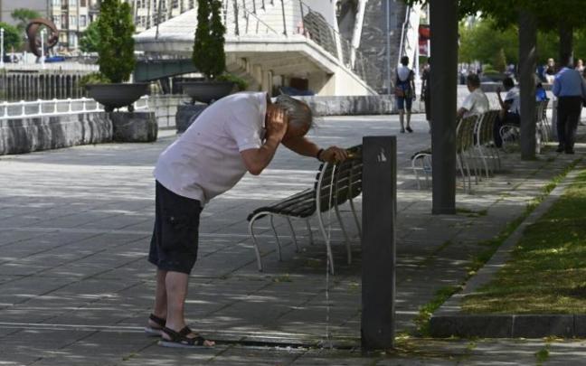 Un hombre se refresca en la fuente para combatir el calor Un hombre se refresca en la fuente para combatir el calor