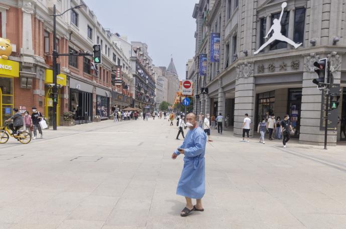 Un hombre con un traje de protección camina por una calle de Shanghái.