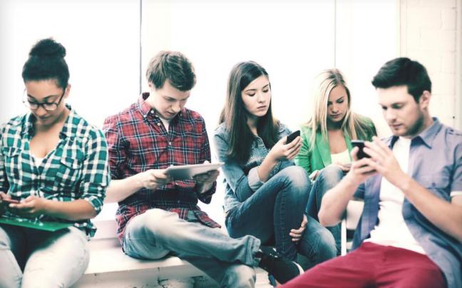 Un grupo de chicos y chicas, cada uno pendiente de su móvil. Un grupo de chicos y chicas, cada uno pendiente de su móvil.