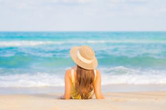 Una mujer, de espaldas, disfruta del sol y de la playa.