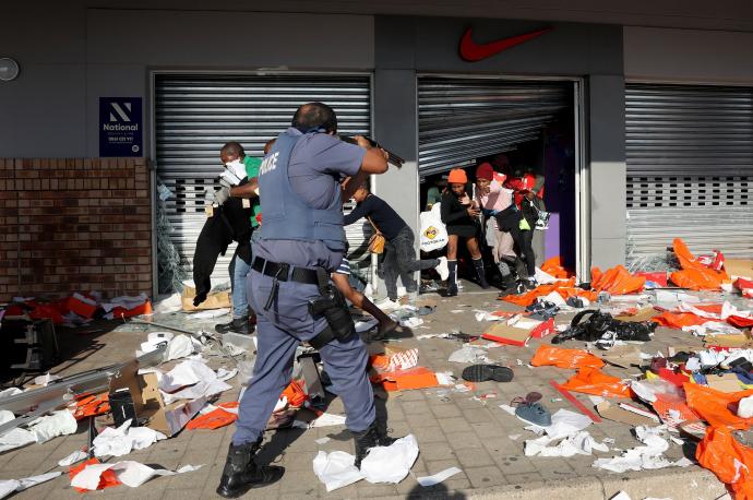 Un agente de policía apunta con su arma a los asaltantes de un comercio en la ciudad de Durban