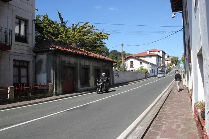 Una motocicleta pasa por delante de la antigua pescadería y charcutería de Sukarrieta.