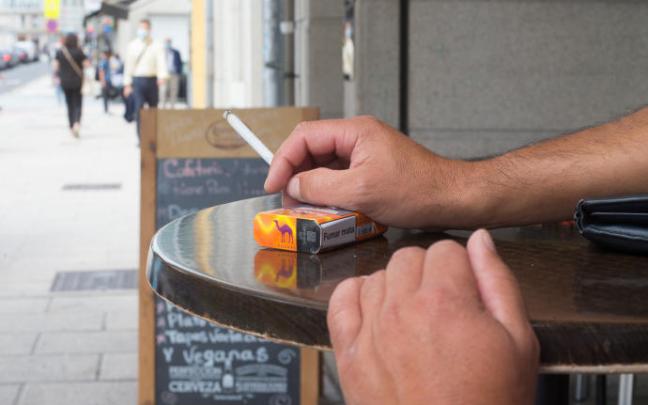 Un hombre fumando en el exterior de un bar. Un hombre fumando en el exterior de un bar.