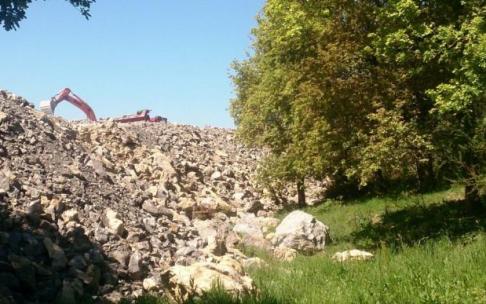 Una excavadora deposita piedras junto a un robledal de Belartza en 2016.