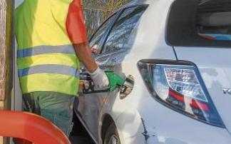 Un hombre echa gasolina a su coche.
