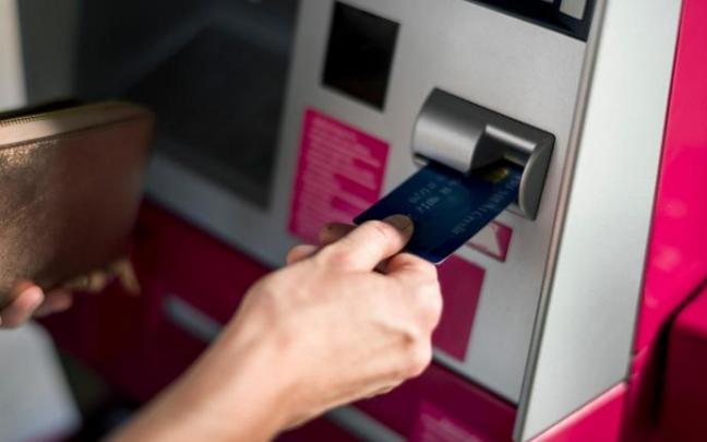 Una persona realiza una operación con su tarjeta en un cajero automático. Una persona realiza una operación con su tarjeta en un cajero automático.
