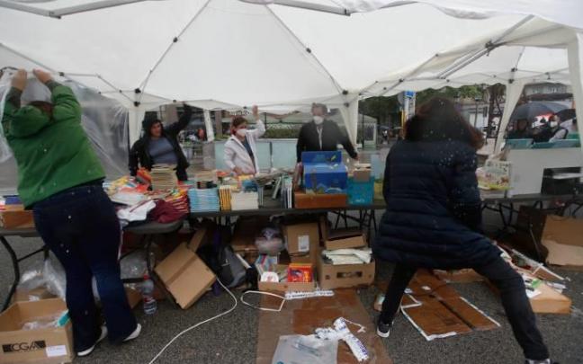 Varios libreros protegen su puesto tras la fuerte granizada caída en Barcelona.