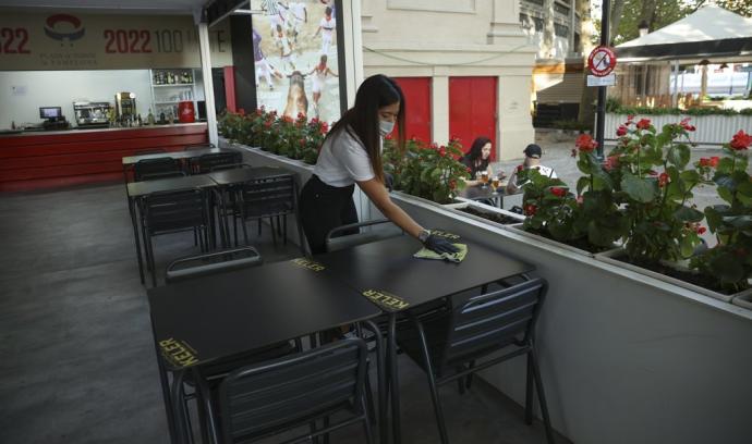 Una camarera limpia las mesas de una terraza instalada junto a la Plaza de Toros.