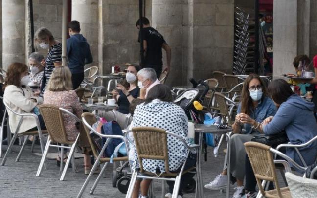 Personas sentadas en la terraza de un bar con mascarilla.