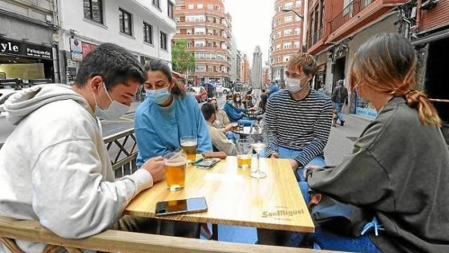 Varios jóvenes se reúnen en la terraza de un bar.