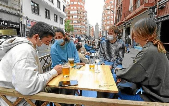 Varios jóvenes se reúnen en la terraza de un bar.