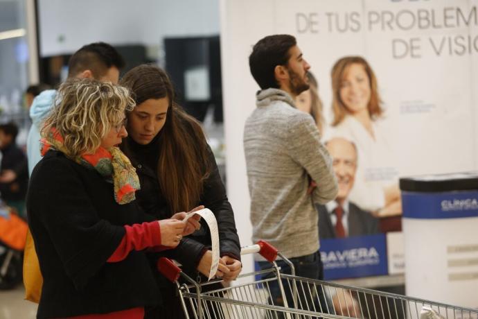 Dos clientes comprueban el ticket de la compra tras pagar en caja