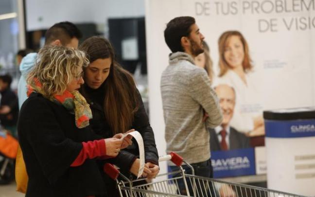 Dos clientes comprueban el ticket de la compra tras pagar en caja
