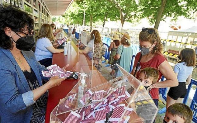 Una voluntaria de Cáritas entrega un puñado de boletos a una madre y sus dos hijos. Una voluntaria de Cáritas entrega un puñado de boletos a una madre y sus dos hijos.