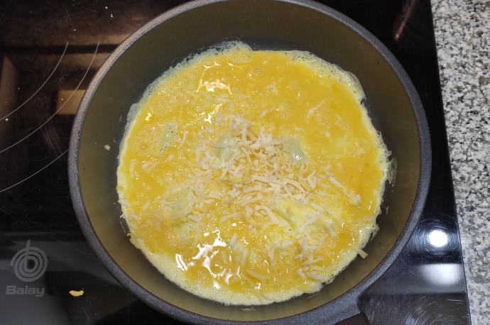 El queso, rallado en lascas o en loncha, se puede añadir tanto en el momento de batir el huevo como ya en la sartén.