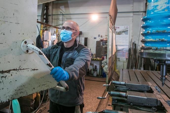 Un operario trabaja con mascarilla en un taller.
