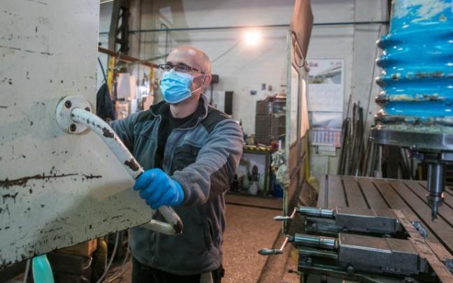 Un operario trabaja con mascarilla en un taller.