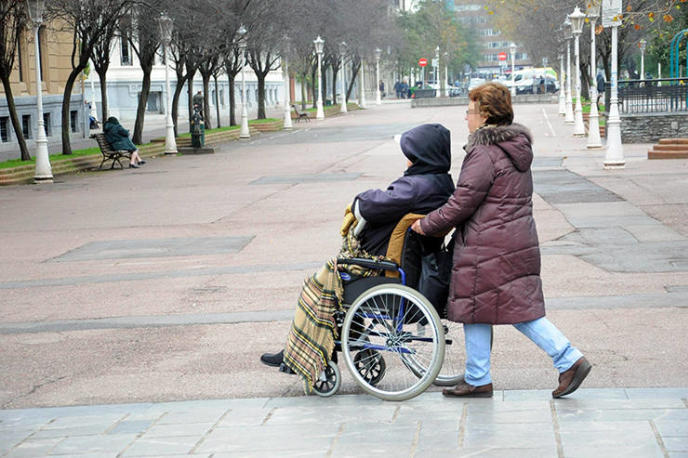 Una mujer atendiendo a una persona dependiente durante un paseo