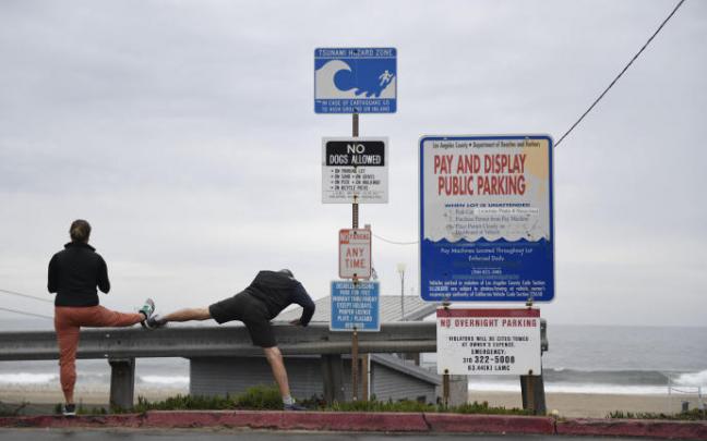 Dos personas hacen deportes junto a un cartel que alerta del peligro de tsunami en California. Dos personas hacen deportes junto a un cartel que alerta del peligro de tsunami en California.