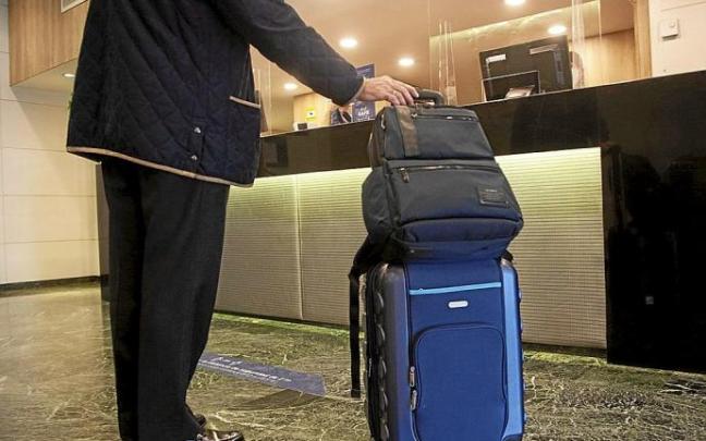 Lerro hauekin batera dagoen irudian, pertsona bat hotel batera iristen, maletekin. Argazkia: Jorge Muñoz