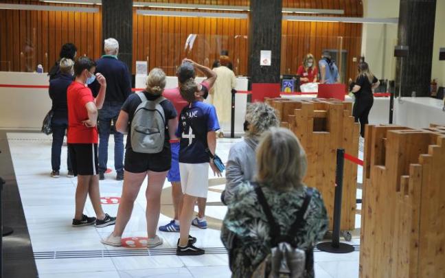 Turistas nacionales e internacionales hacen cola en la Oficina de Turismo de Bilbao.