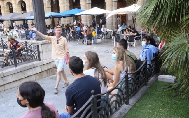 Un guía da explicaciones a varios turistas en una Plaza Nueva con las terrazas abarrotadas.