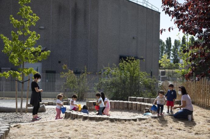 Niños y niñas de la escuela infantil de Mendillorri con dos monitoras en el recreo.