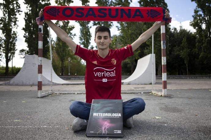 Arnaitz Fernández con la camiseta y la bufanda de Osasuna y un libro de meteorología