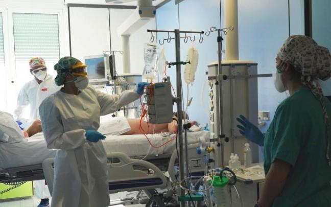 Varios sanitarios atienden a un paciente en UCI. Varios sanitarios atienden a un paciente en UCI.