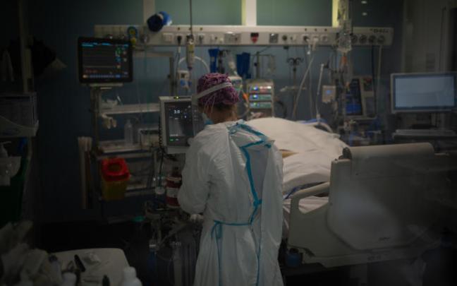 Trabajadores sanitarios protegidos atienden a un paciente en la Unidad de Cuidados Intensivos Trabajadores sanitarios protegidos atienden a un paciente en la Unidad de Cuidados Intensivos
