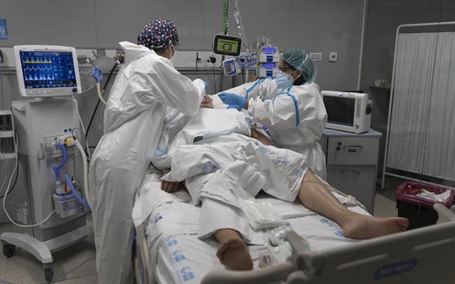 Dos sanitarias atienden a un hombre ingresado en la UCI.