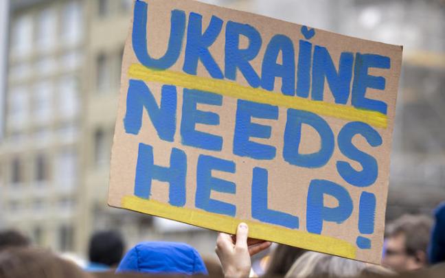 Un manifestante sostiene un cartel que solicita ayuda para Ucrania.