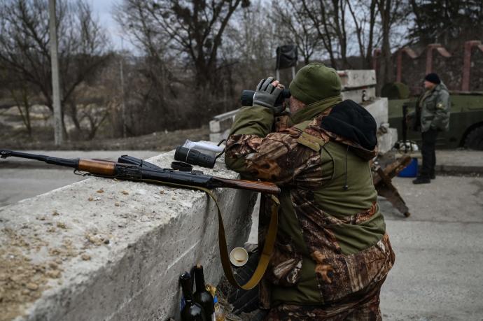 Un militar ucraniano observa con unos prismáticos.