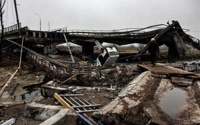 Un hombre camina junto a un puente destruido cerca de la ciudad de Irpin.