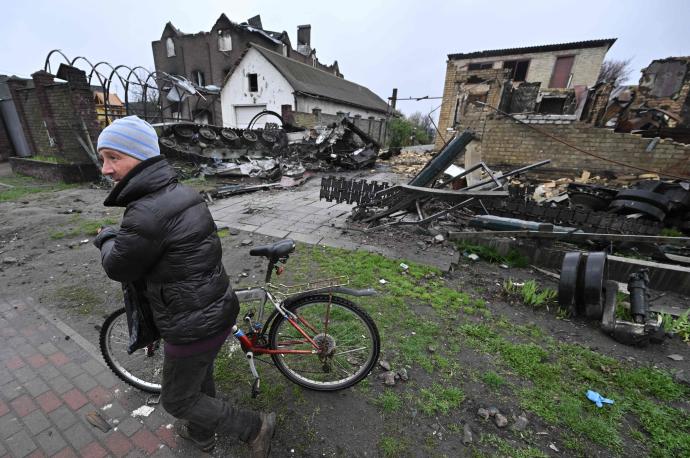 Un hombre empuja su bicicleta frente a edificios destruidos cerca de Kiev.