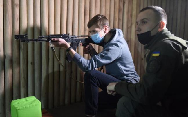 Un militar ucraniano enseña a un joven a disparar con un Kalashnikov.