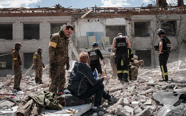 Soldados ucranianos buscan supervivientes entre los escombros de una escuela destruida.