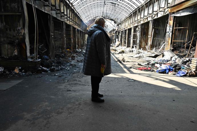 Una mujer observa los destrozos provocados por un bombardeo en un mercado de Jarkóv.