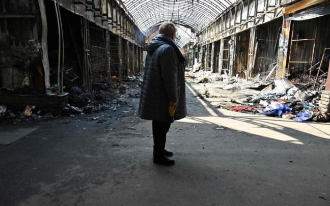 Una mujer observa los destrozos provocados por un bombardeo en un mercado de Jarkóv.